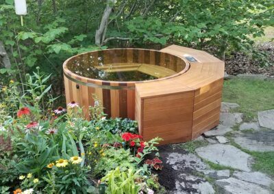 single wall hot tub set in a garden with colorful flowers